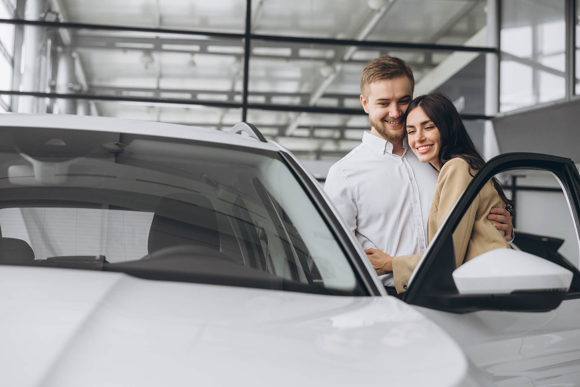 Happy couple embracing beside their car.