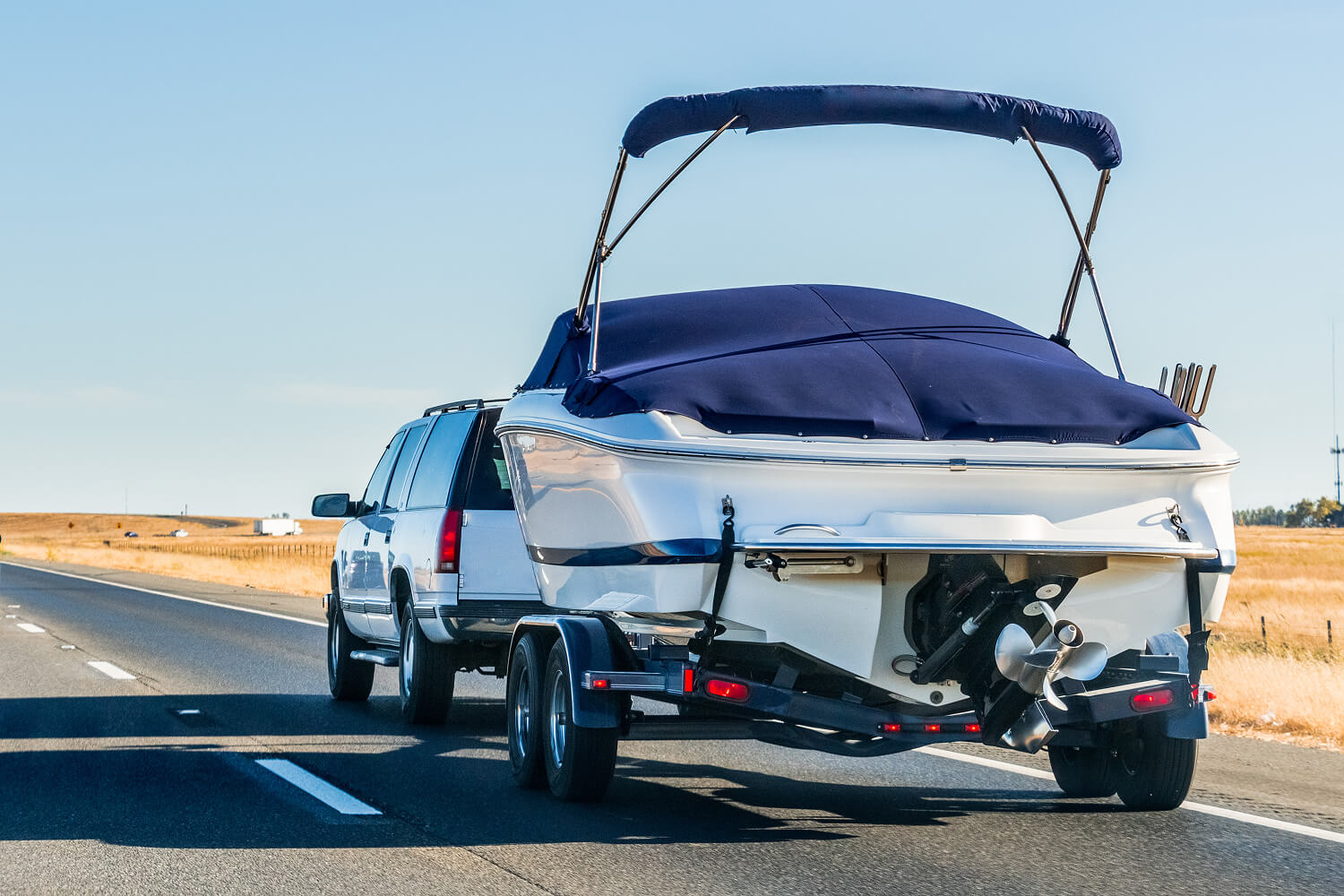Truck towing a boat on the highway.