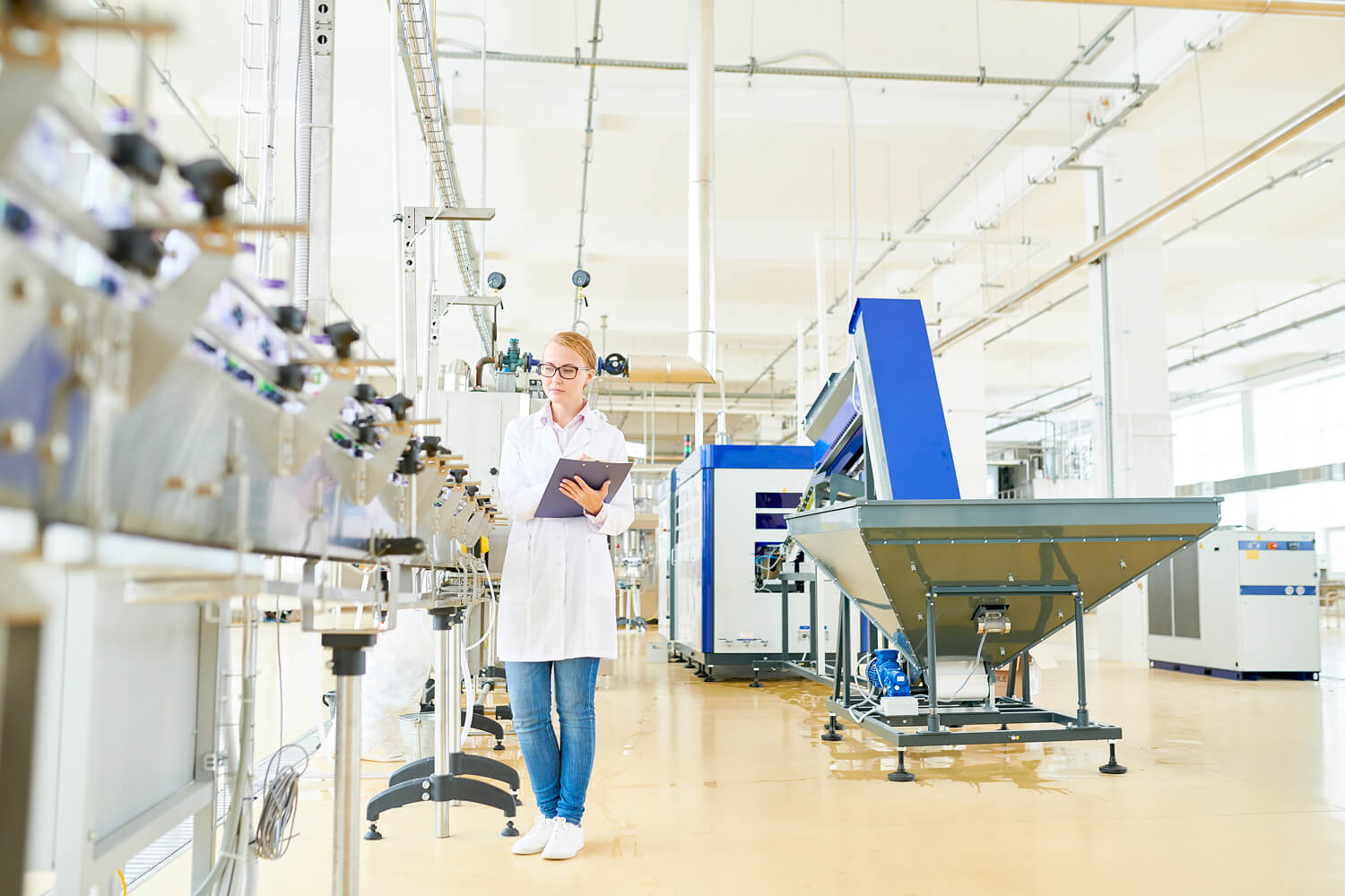 Woman inspecting manufacturing equipment in a factory.