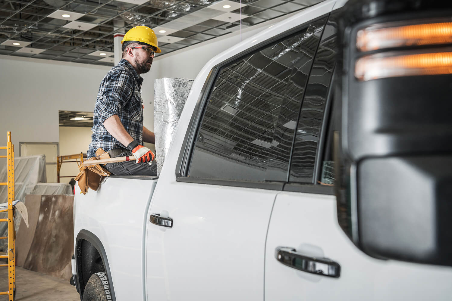 Construction worker sitting on a work truck with insulation materials.