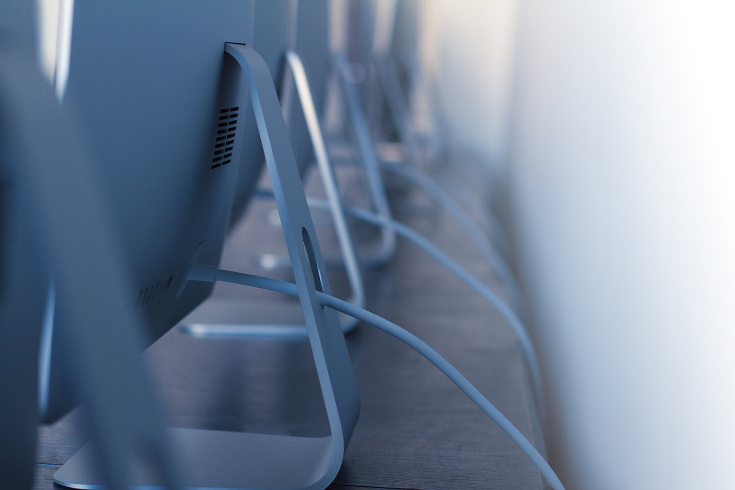 Row of desktop computers on office desks.