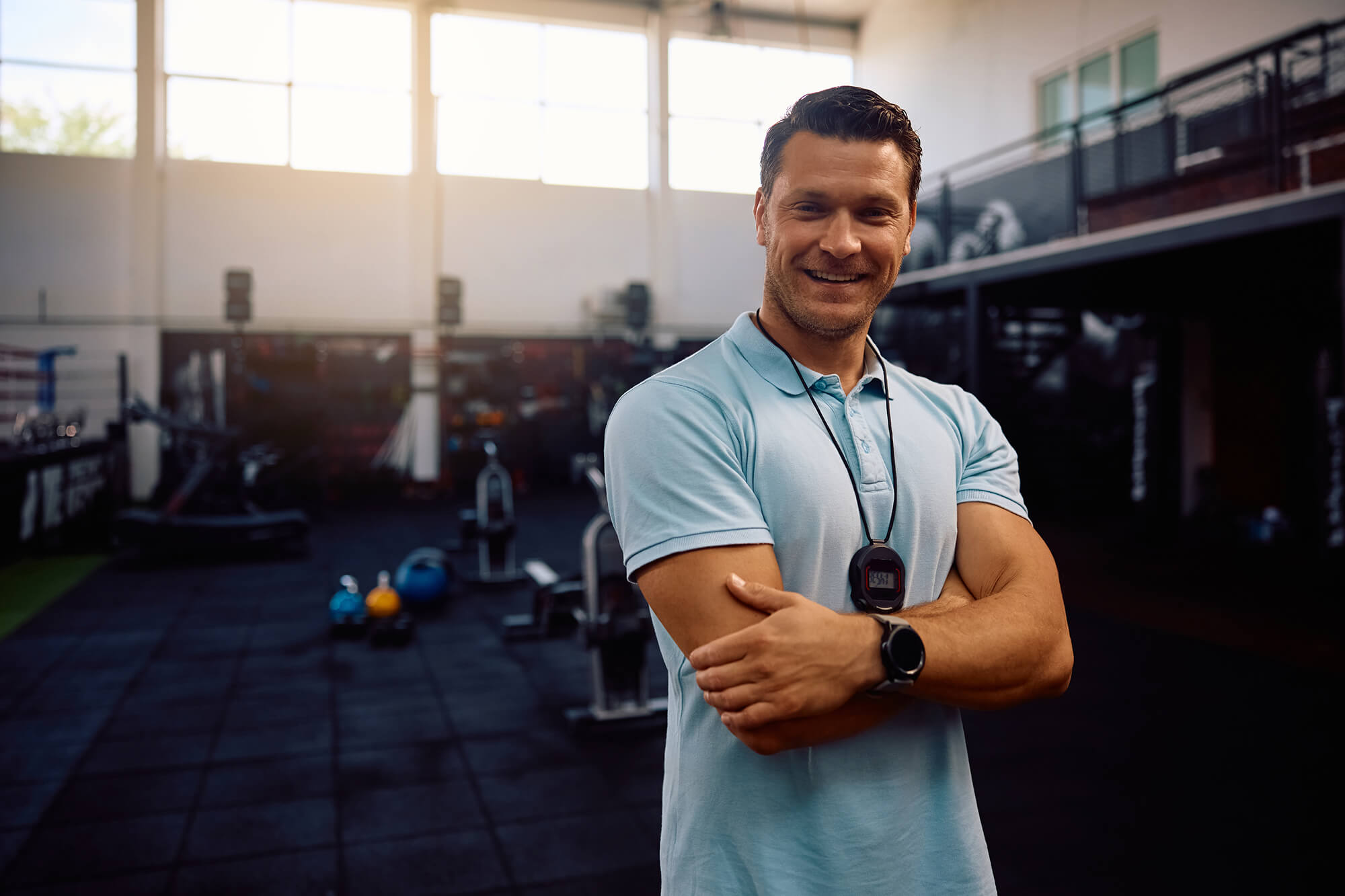 Portrait of a smiling fitness instructor with arms crossed.