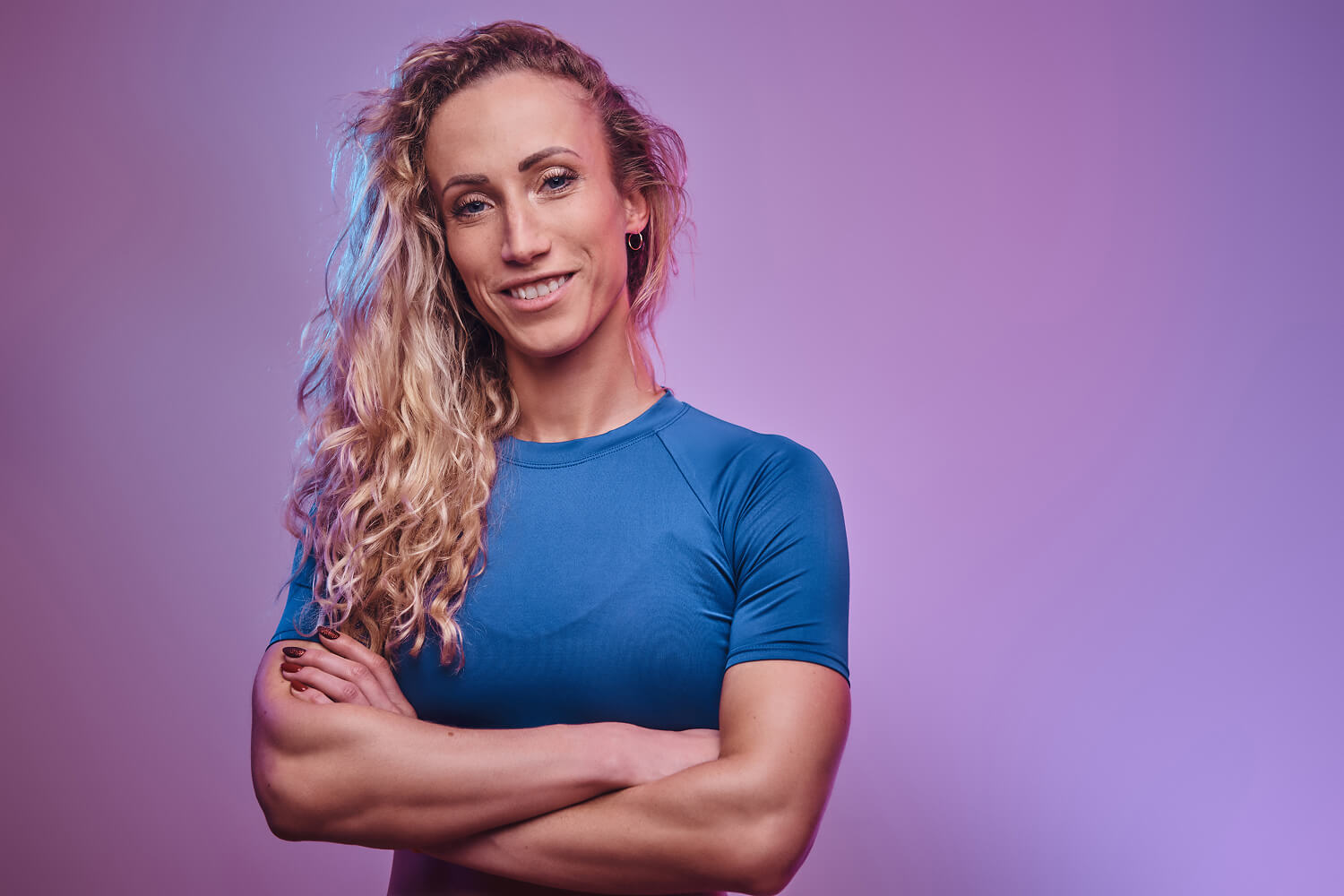 Woman in a blue shirt posing with arms crossed.
