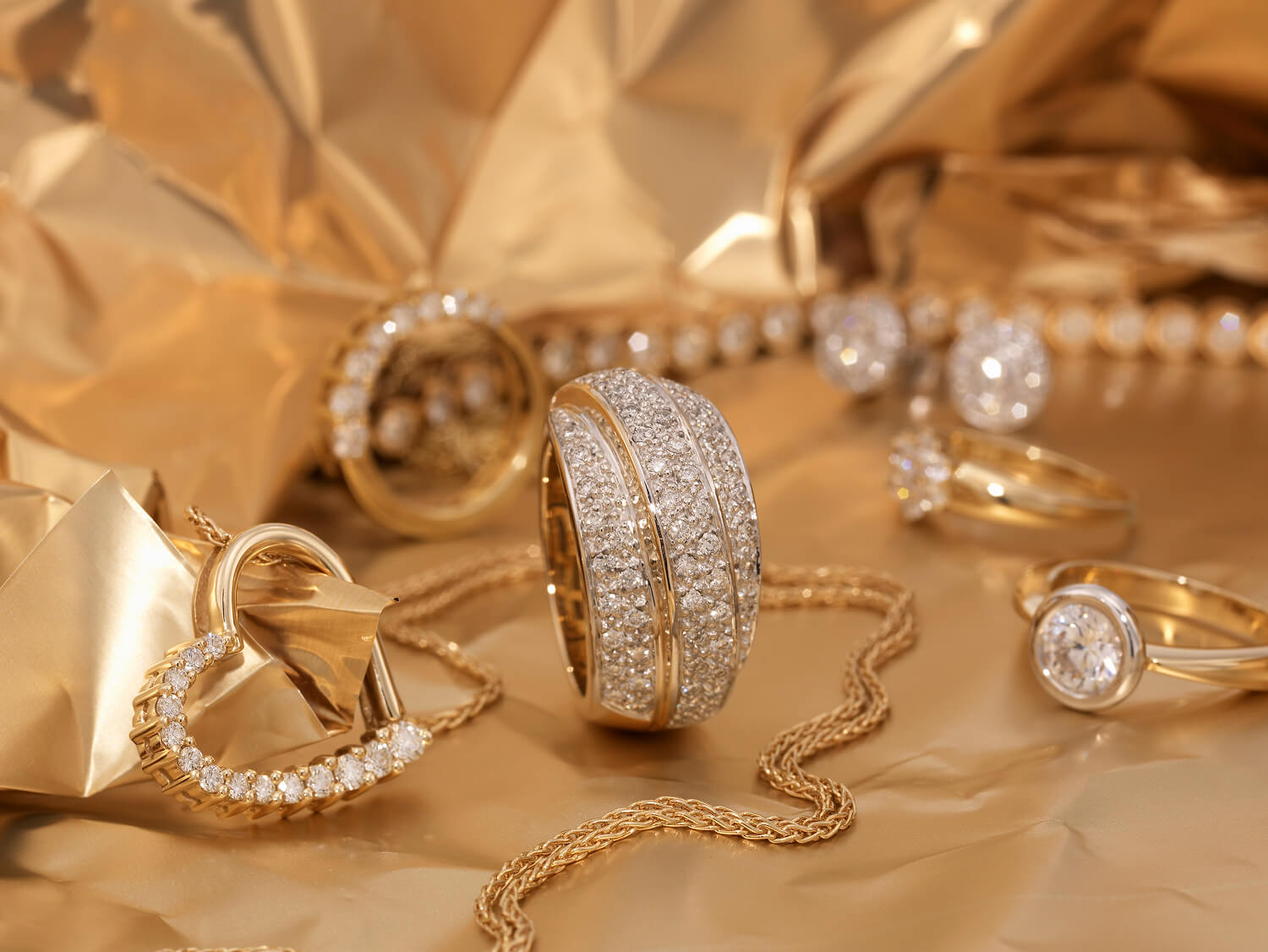 Elegant gold jewelry on a shimmering gold background.