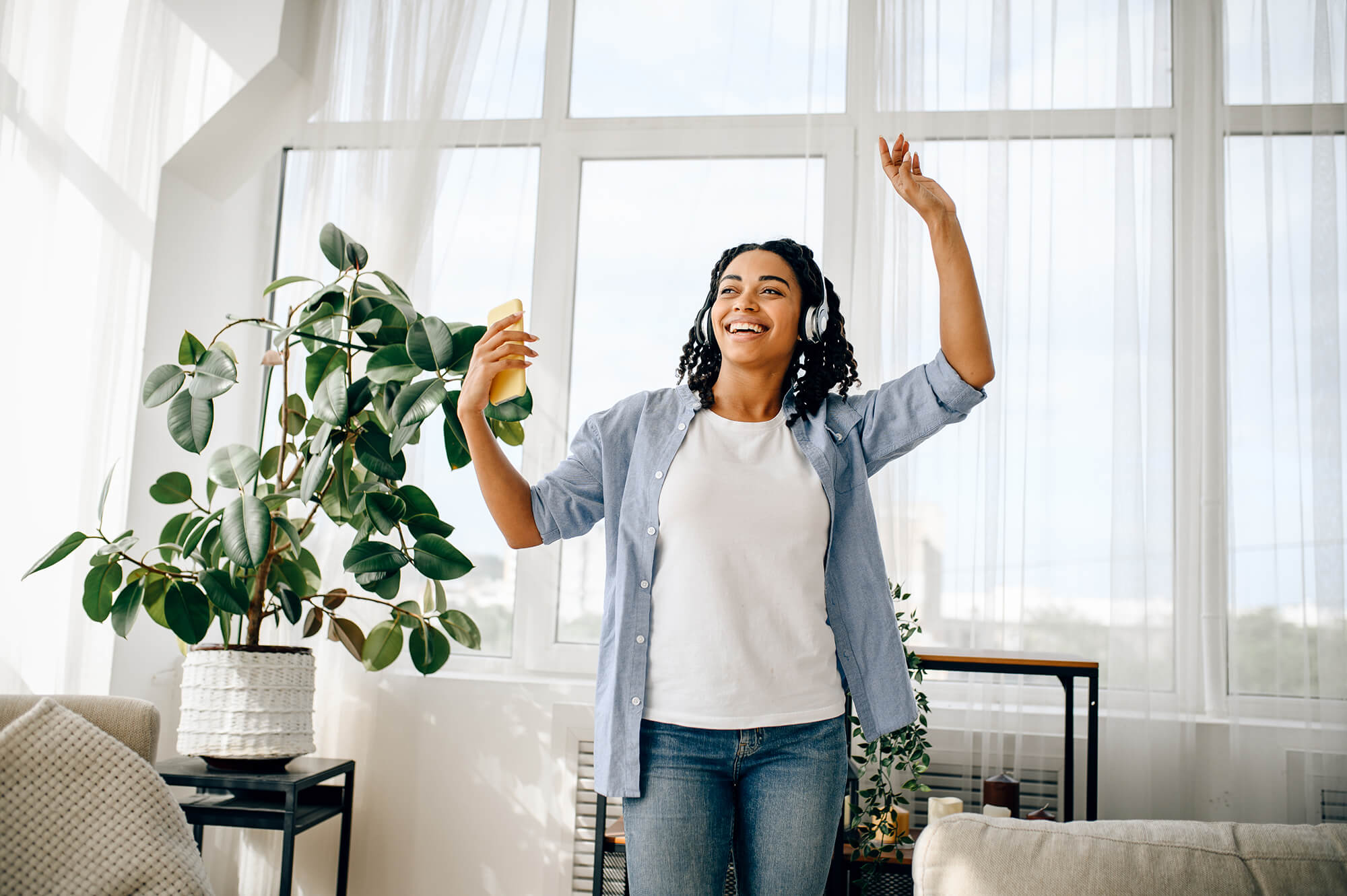 Woman dancing and enjoying music in a bright apartment.
