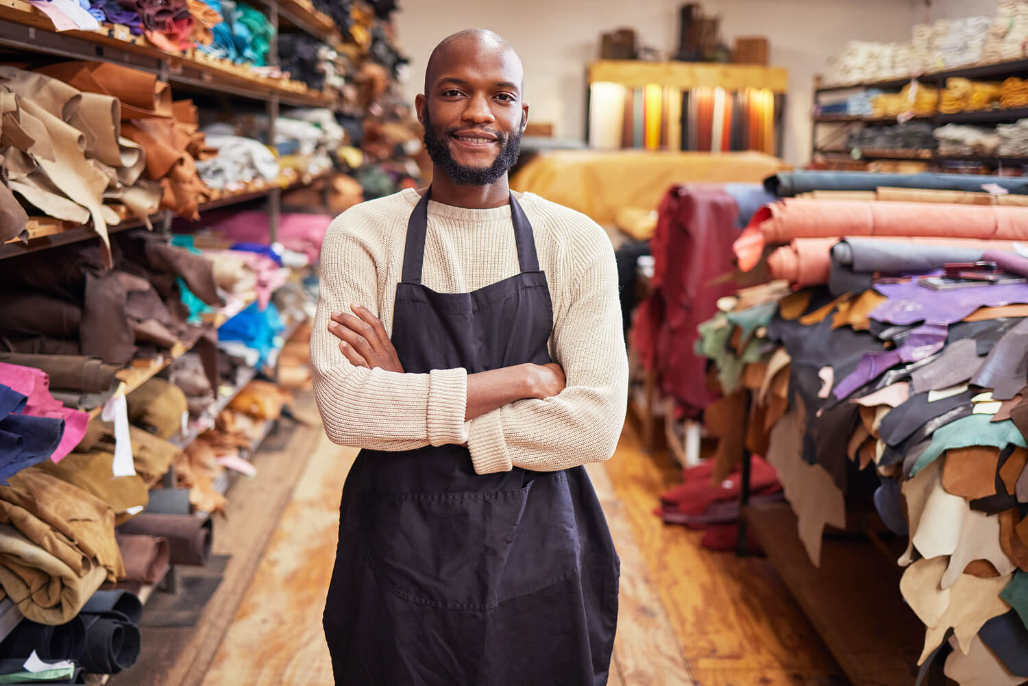 A store owner smiling with his arms folded.