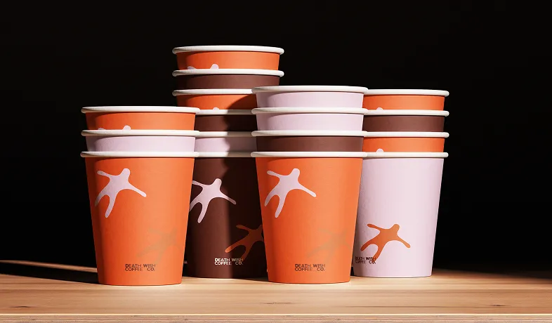 Stacked peach, brown, and light pink Death Wish Coffee Co. paper cups on a wooden surface.