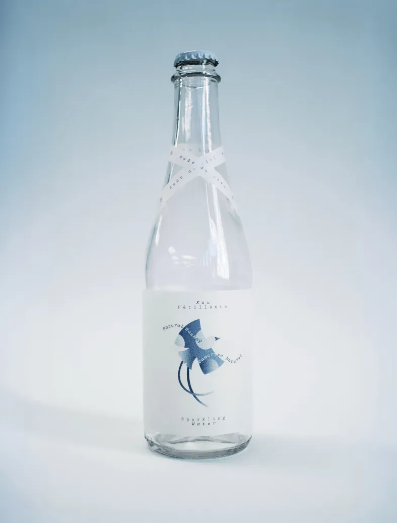Clear glass bottle of sparkling water with a white label featuring a blue abstract design.