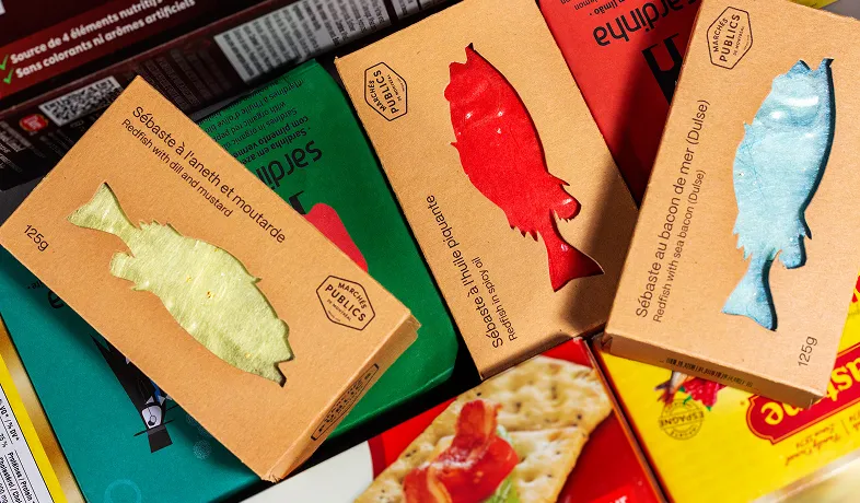 Boxes of redfish with various seasonings stacked on colorful food packaging in a display.
