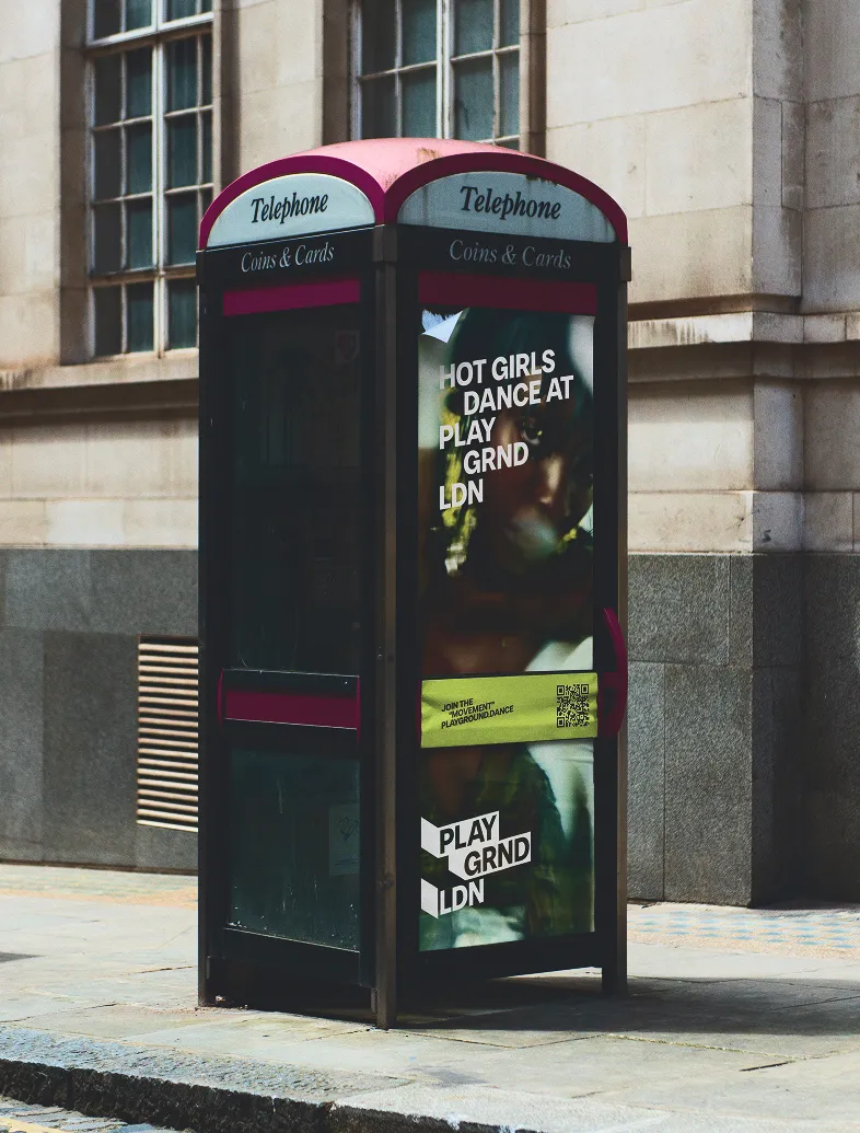 Classic British telephone booth on the street with dance event ads on the glass panels.
