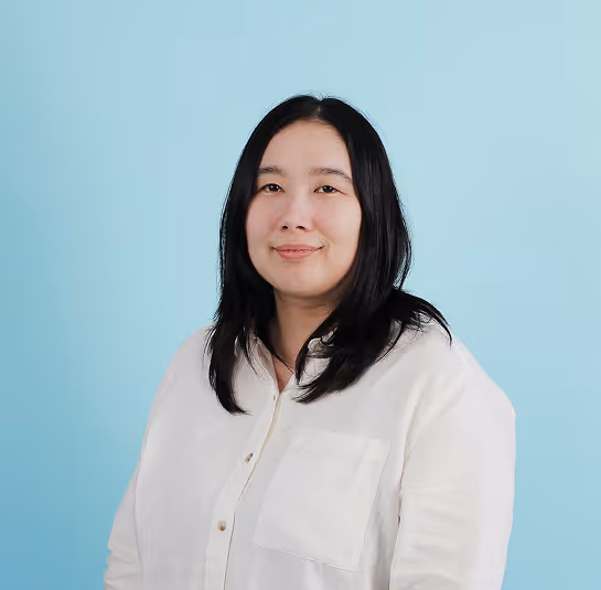 Portrait of a woman with black hair wearing a white shirt against a light blue background.
