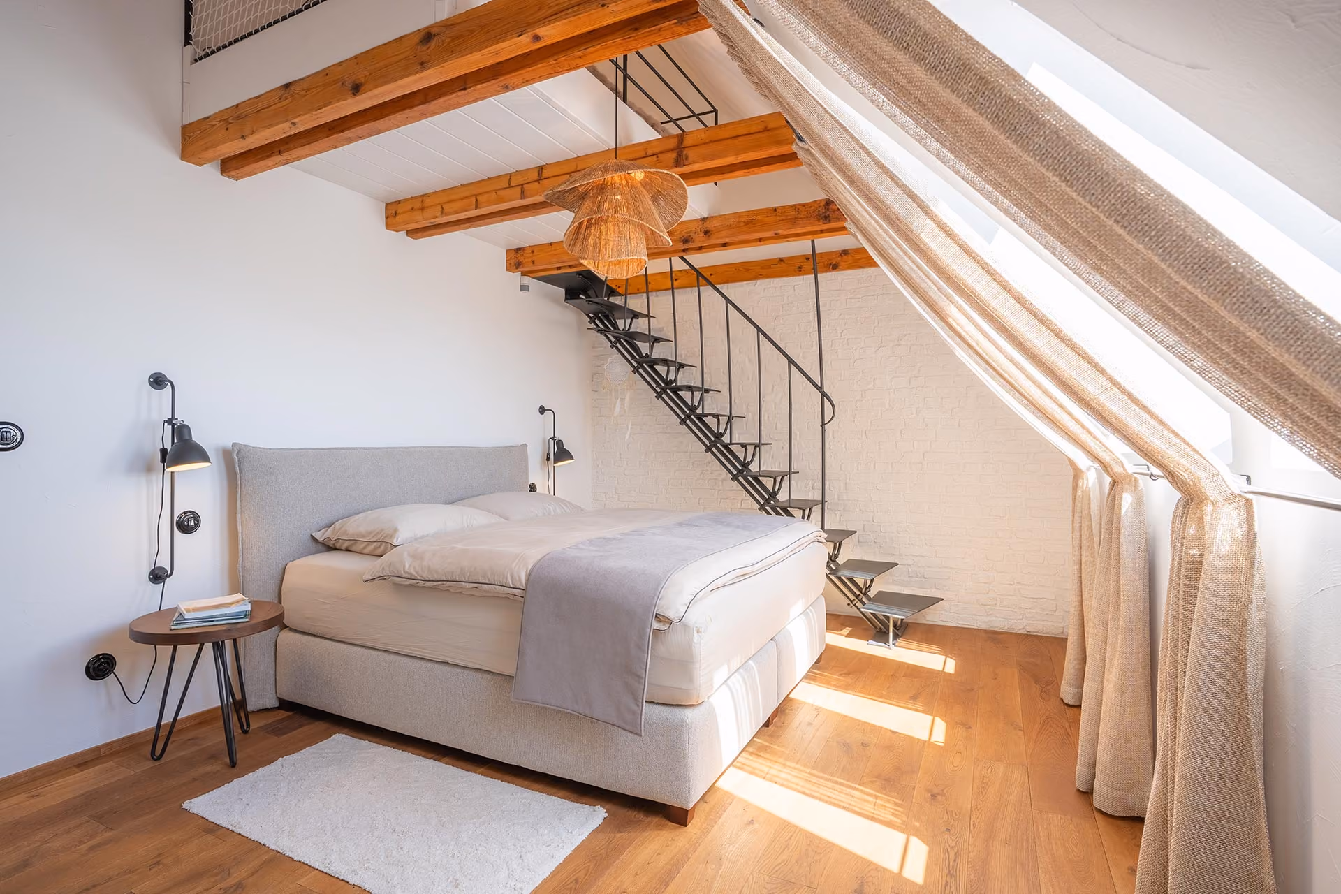Loft so zachovanými drevenými trámami, kovovým schodiskom a strešnými oknami
