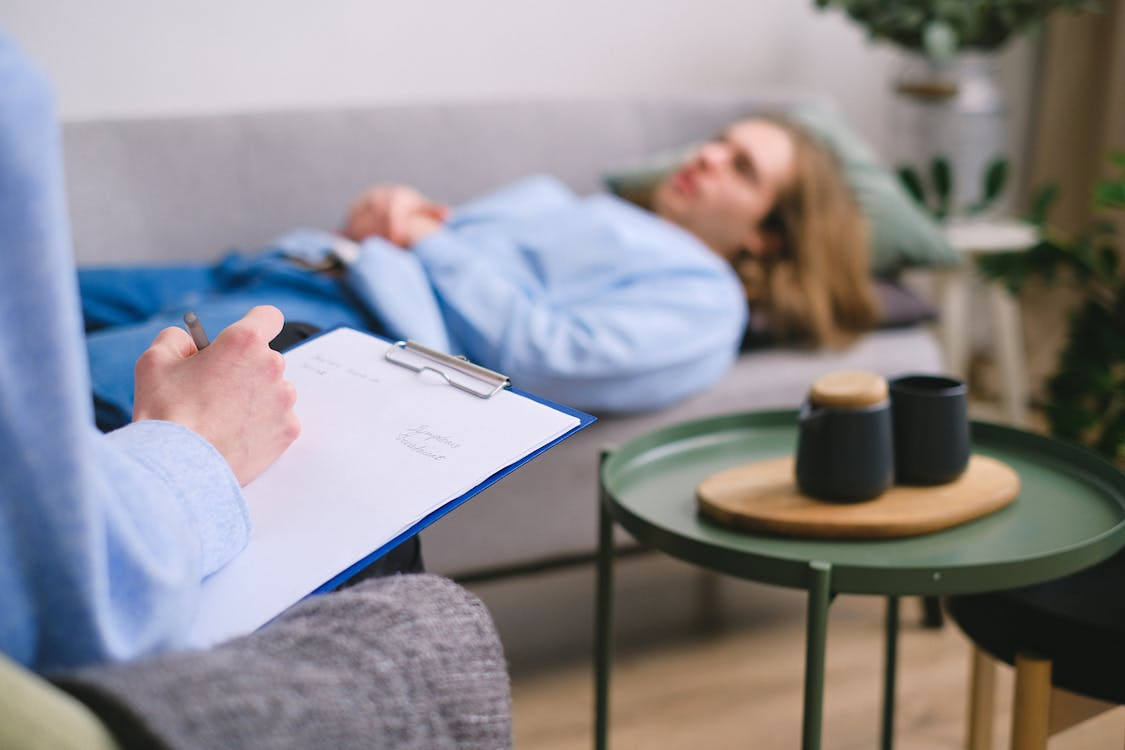 A person holds a clipboard labeled "Session Notes" while another reclines on a couch.