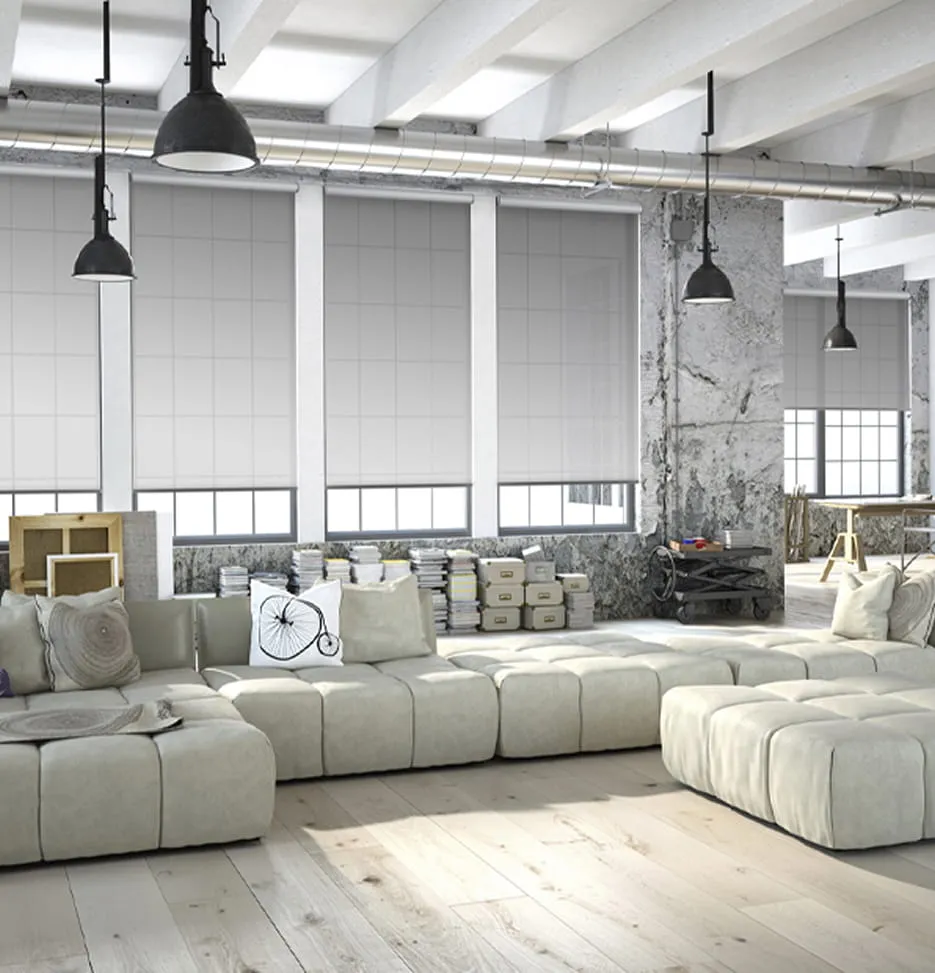 Modern industrial living space with beige modular sofa, large windows with blinds, and pendant lights.