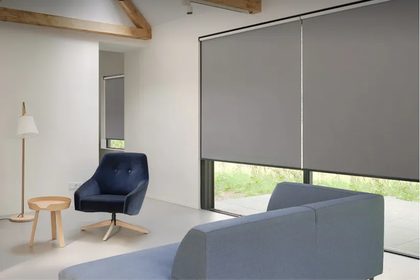 Minimalist living room with gray sofa, navy blue armchair, wooden side table, and tall floor lamp.