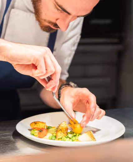 A chef in uniform delicately puts the finishing touches on the presentation of a colorful gourmet dish. Les Hauts de Loire – 5-star Hotel, Restaurant & Spa.