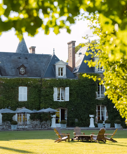 Façade arrière du château recouverte de lierre, vue encadrée par le feuillage vert. Les Hauts de Loire – Hôtel, Restaurant & Spa – 5 étoiles.