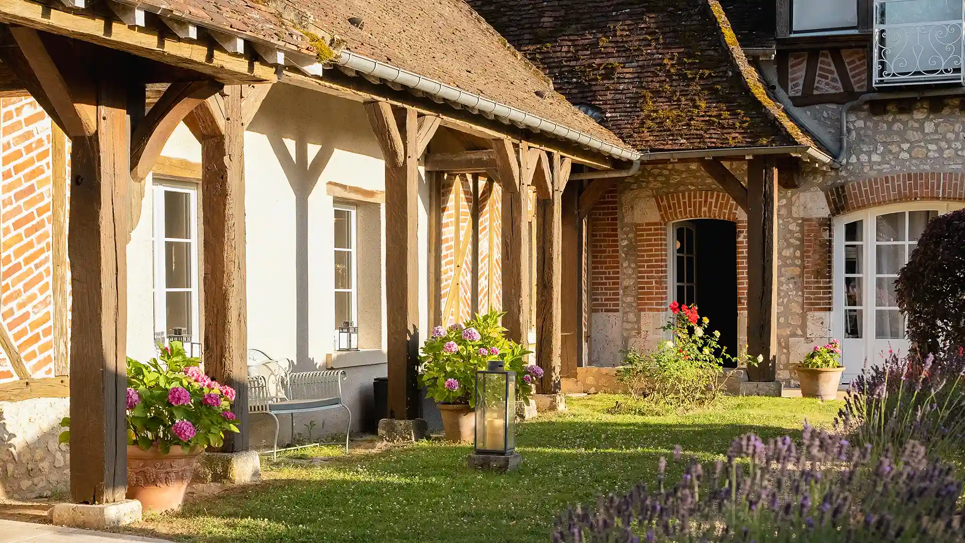 El balcón exterior de madera, bañado por el sol, de una habitación del hotel de 5 estrellas Les Hauts de Loire (hotel, restaurante y spa), que ofrece una vista parcial del césped y de la lavanda.