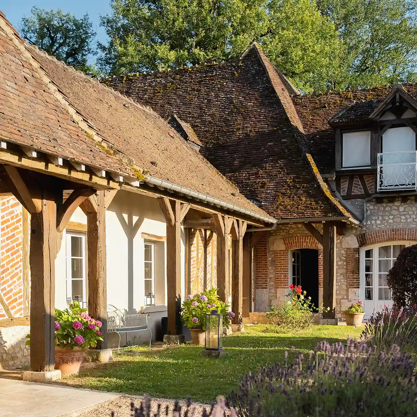 Une vue rapprochée de la façade à colombages et briques de chambre à l'hôtel Les Hauts de Loire – Hôtel, Restaurant & Spa – 5 étoiles, avec des fleurs en pot et de la lavande au premier plan.