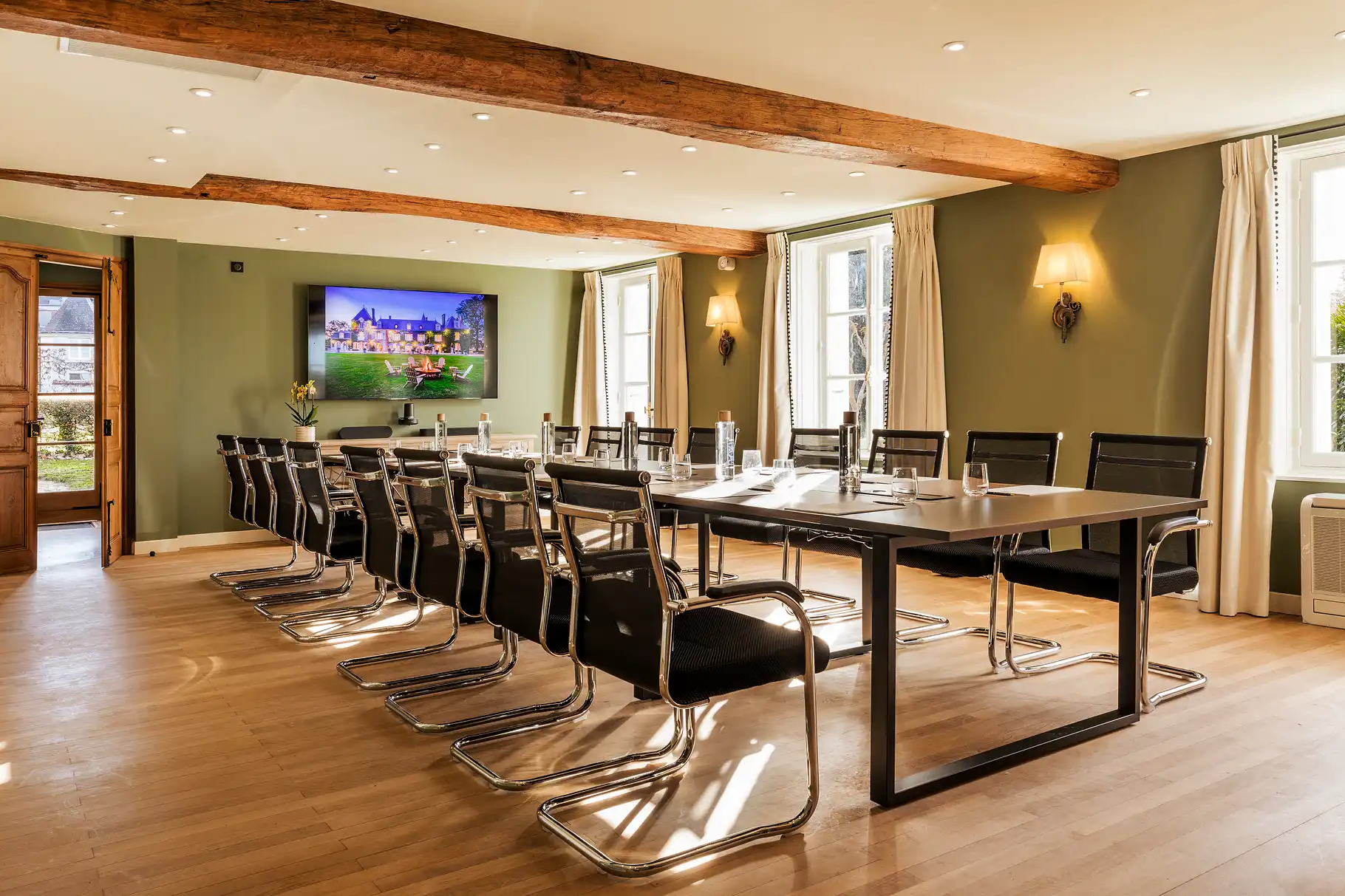 Seminarraum, ausgestattet mit einem langen Besprechungstisch, schwarzen Stühlen und einem an der Wand montierten Bildschirm, im Les Hauts de Loire – 5-Sterne-Hotel, Restaurant & Spa.
