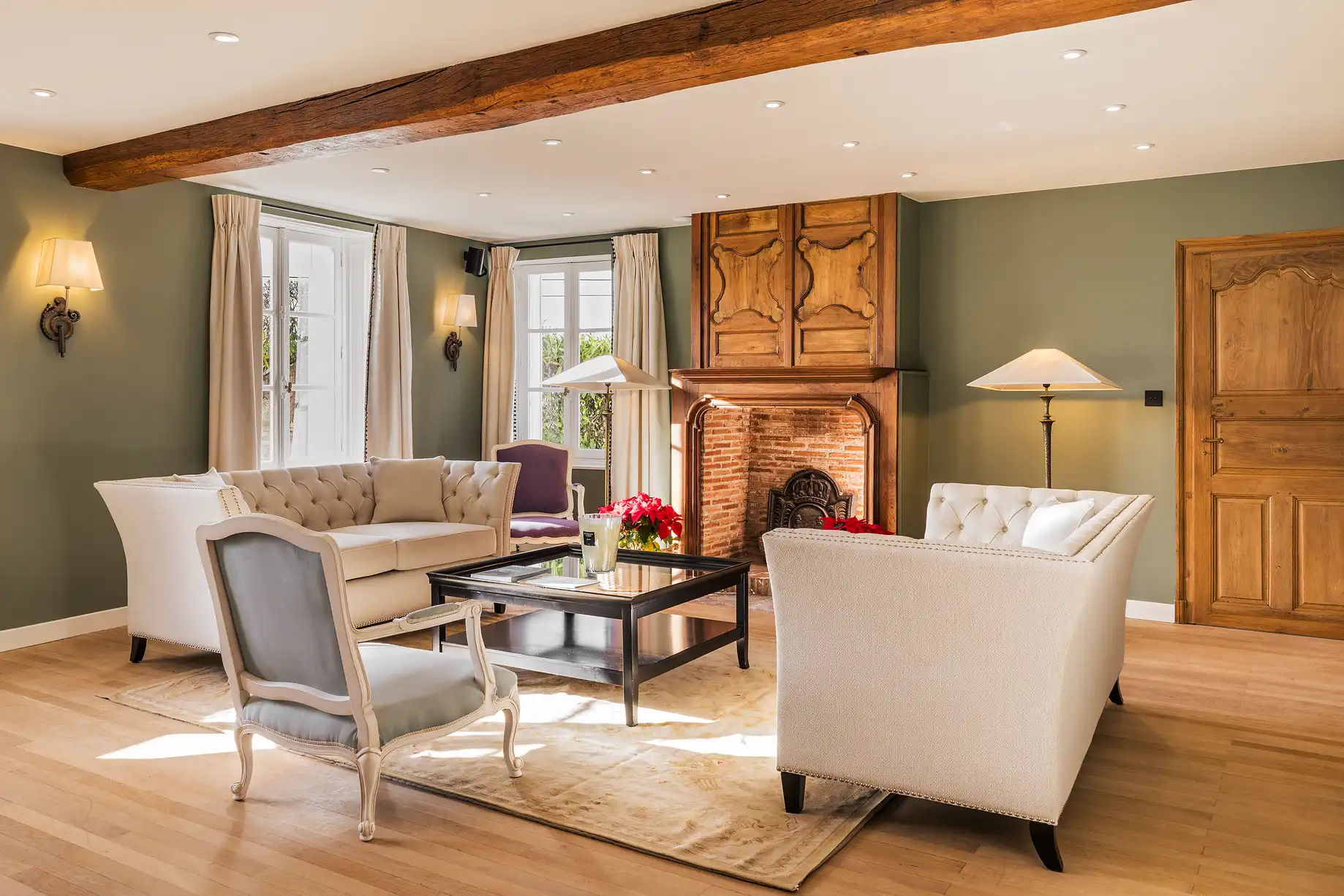 Eleganter Entspannungsbereich mit weißen Sofas, sichtbaren Deckenbalken und einem großen, traditionellen Kamin im Les Hauts de Loire – 5-Sterne-Hotel, Restaurant & Spa.