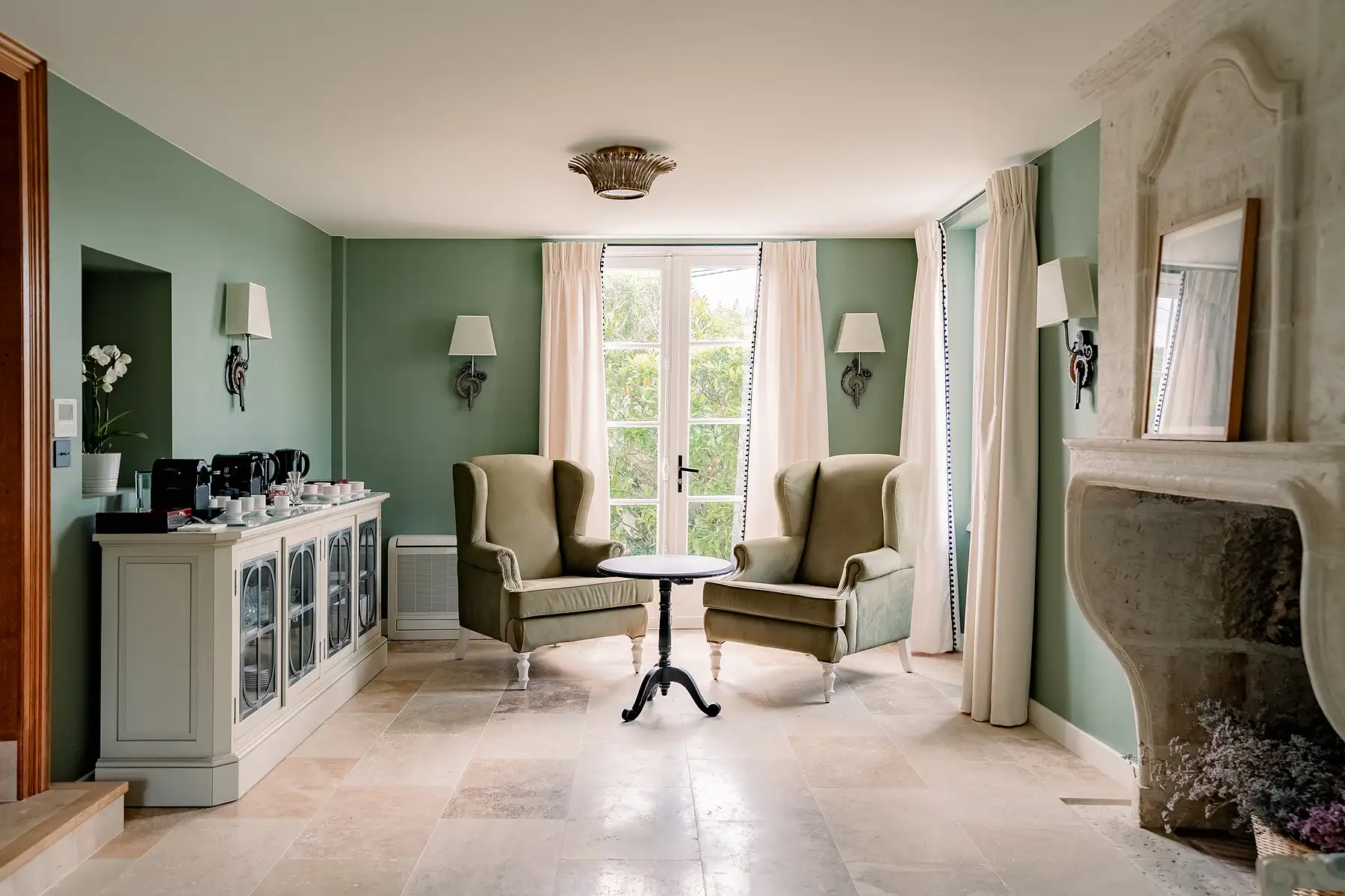 Petit salon vert d'eau avec deux fauteuils confortables près d'une fenêtre lumineuse aux Hauts de Loire – Hôtel, Restaurant & Spa – 5 étoiles.