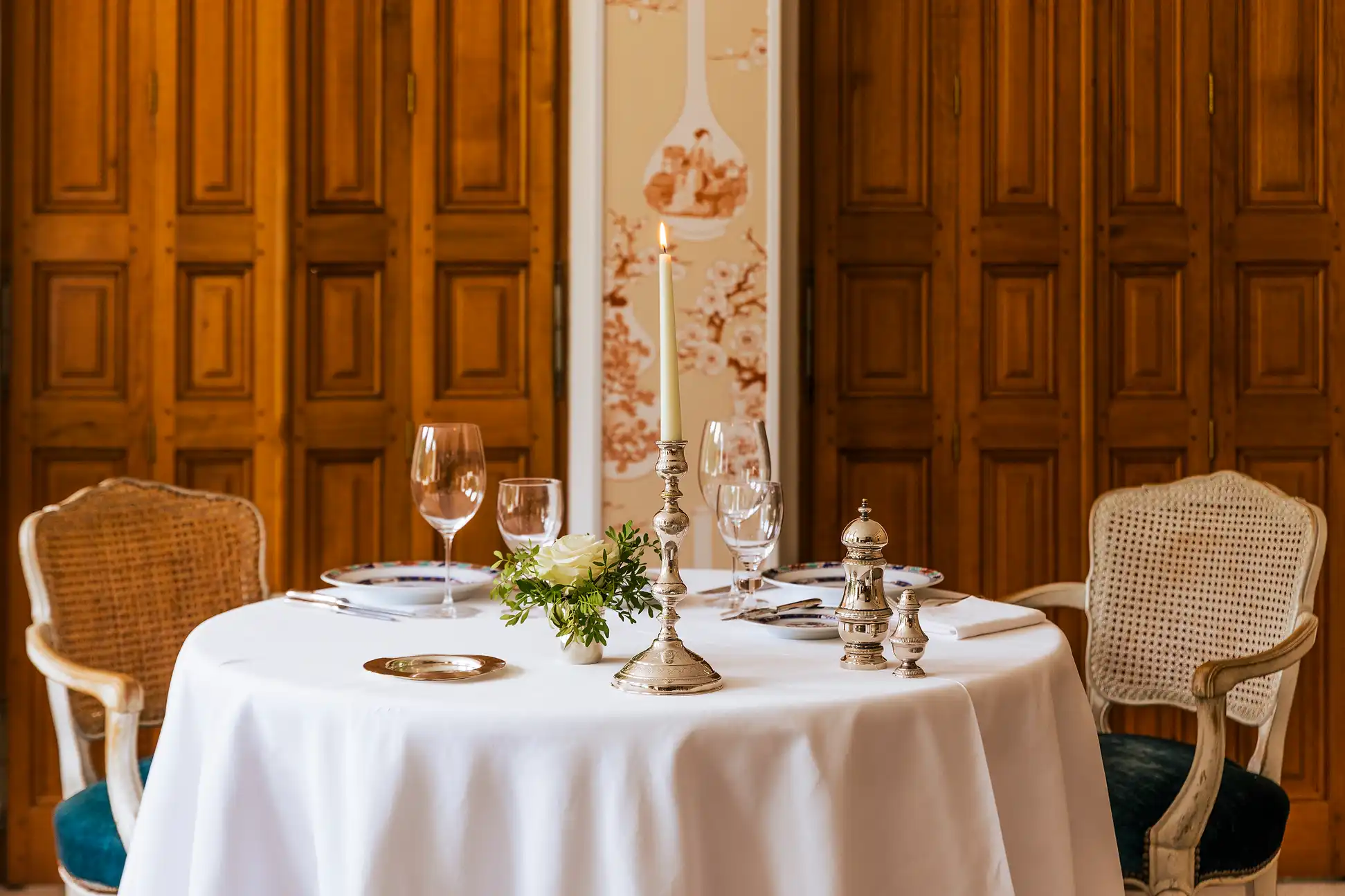 Table du restaurant gastronomique avec arrangement floral et candélabre argenté, devant des boiseries.