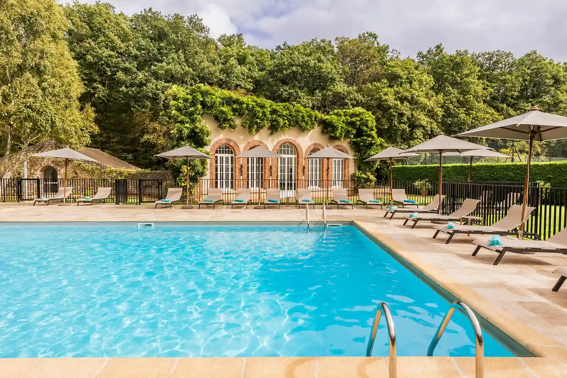 Piscine extérieure bleue entourée de chaises longues aux Hauts de Loire.