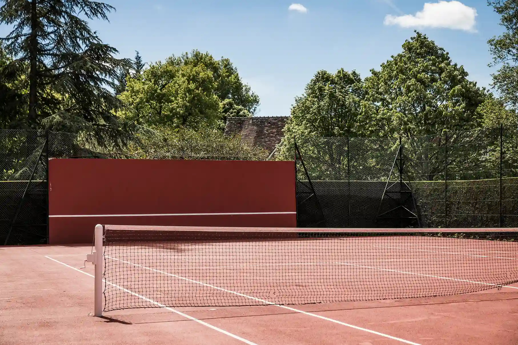 Terrain de tennis extérieur sous un ciel ensoleillé aux Hauts de Loire.