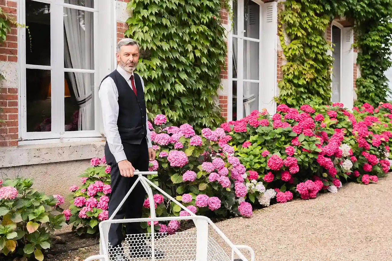 Personnel hôtelier préparant les bagages devant la façade fleurie des Hauts de Loire.