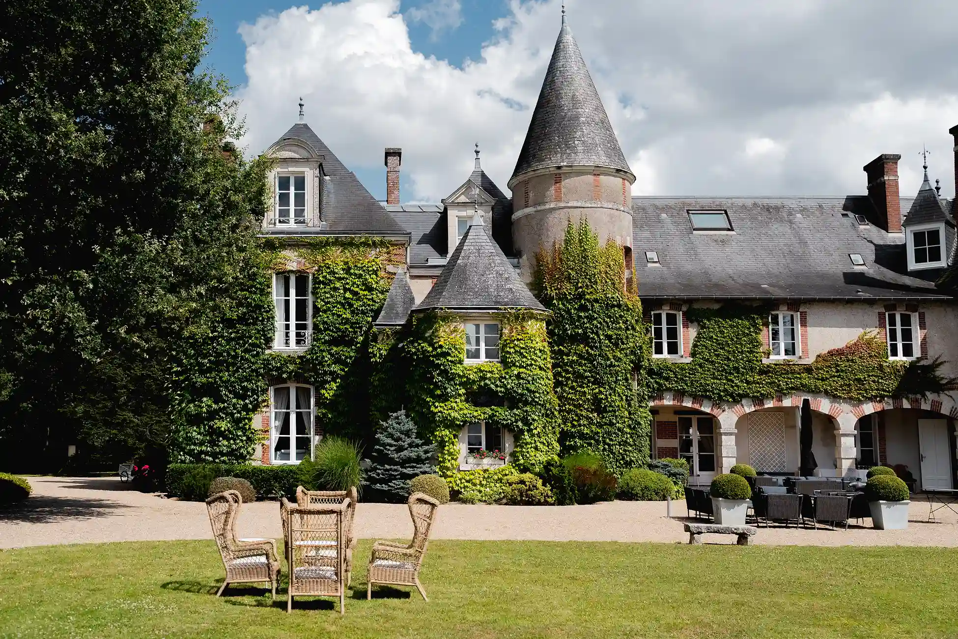 Architektur von Château Les Hauts de Loire, vom Garten aus gesehen, mit Sitzgelegenheiten im Freien.