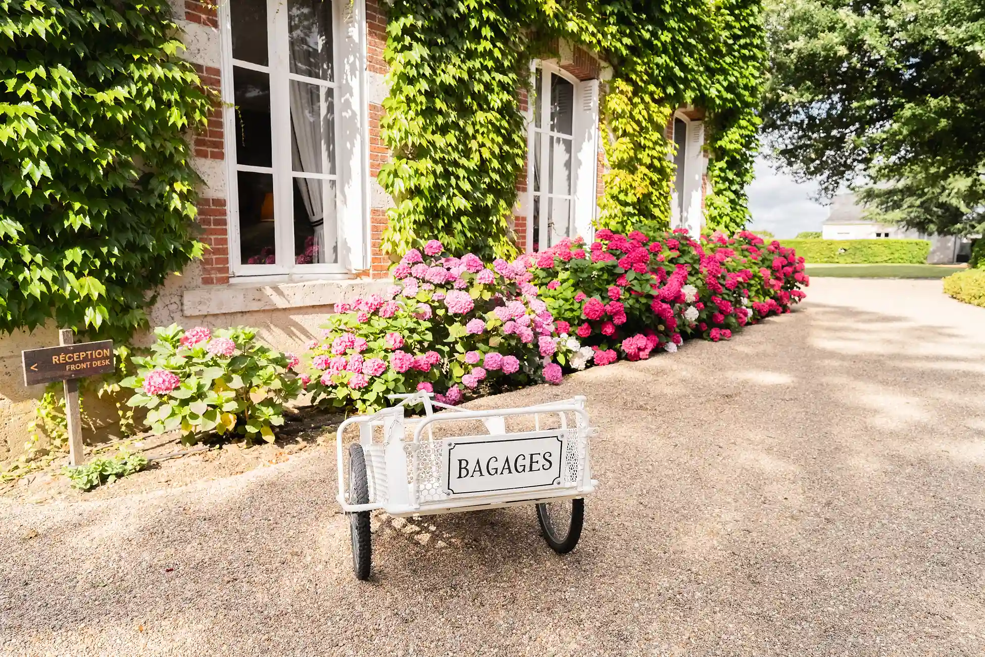 Holzwagen vor einer Blumenwand am Fuß des Gebäudes.
