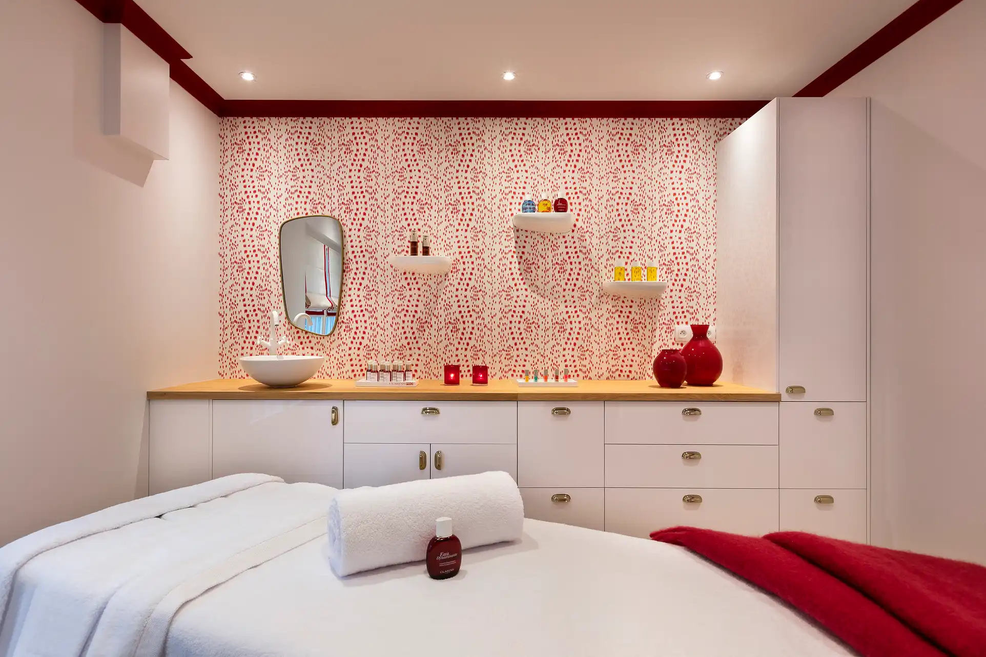 Cabine de spa Les Hauts de Loire avec table de massage, produits rouges et miroir décoratif.