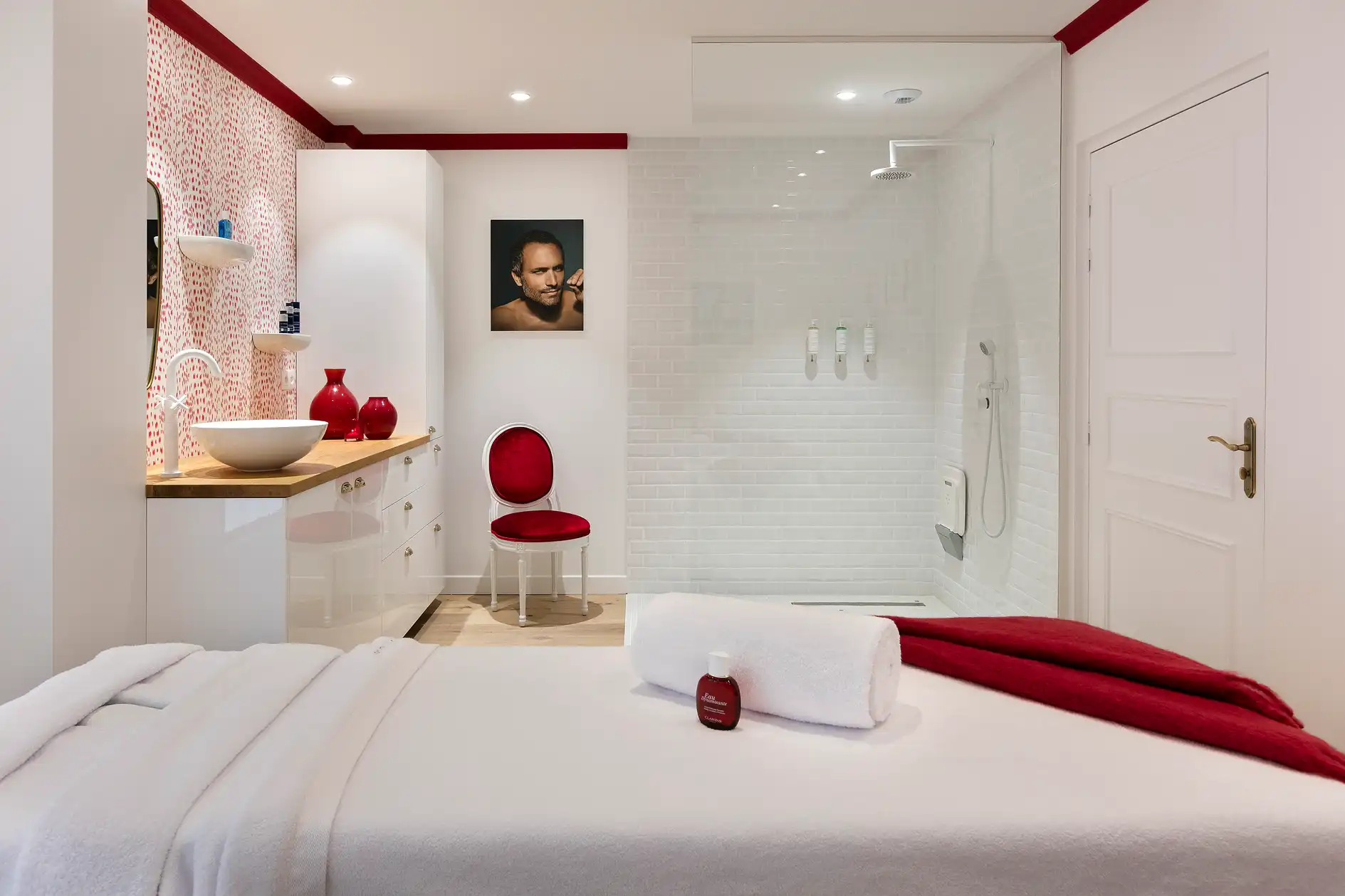 Vue d'une cabine de soin Les Hauts de Loire avec table de massage, lavabo et siège rouge.