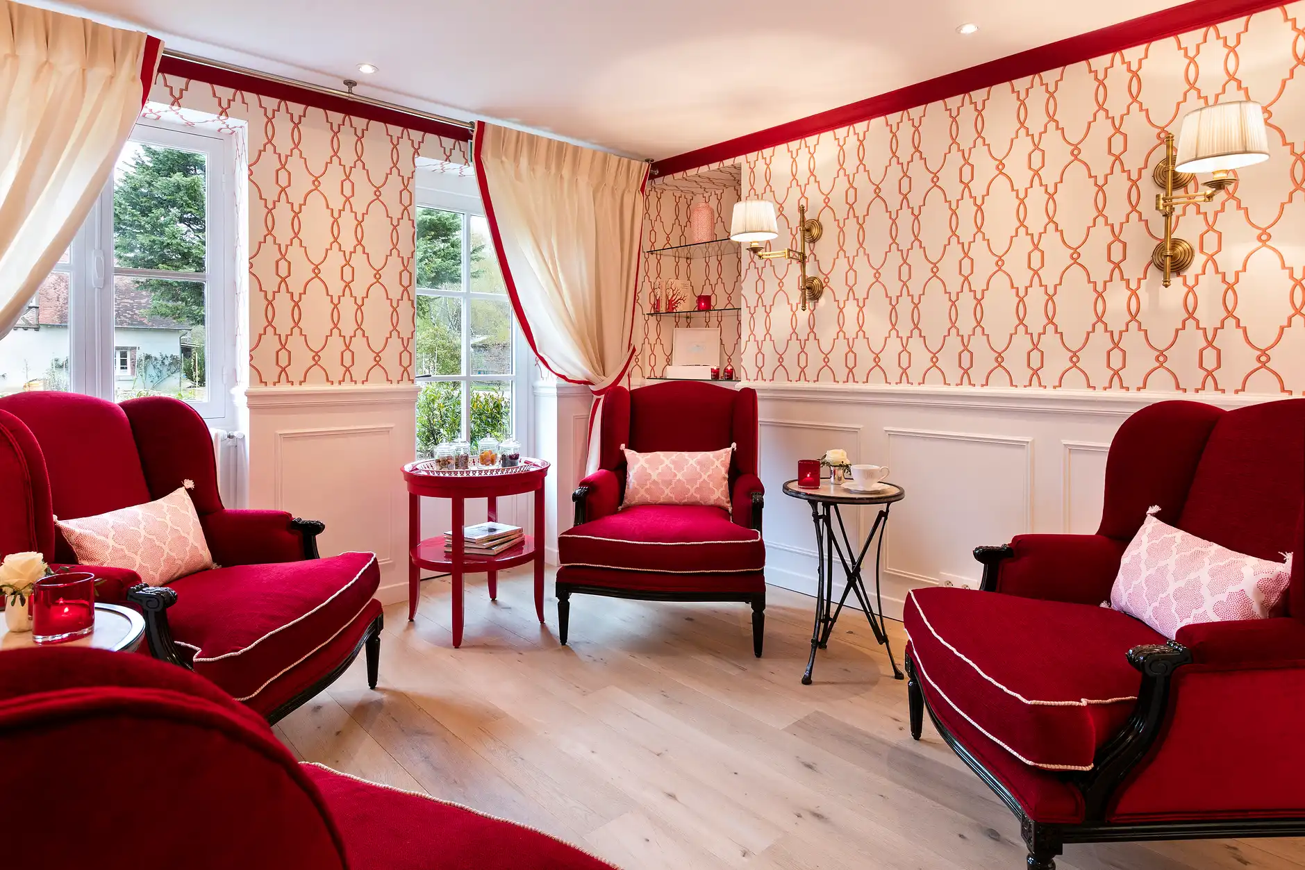 Salon d'attente du spa Les Hauts de Loire avec fauteuils rouges et papier peint élégant.