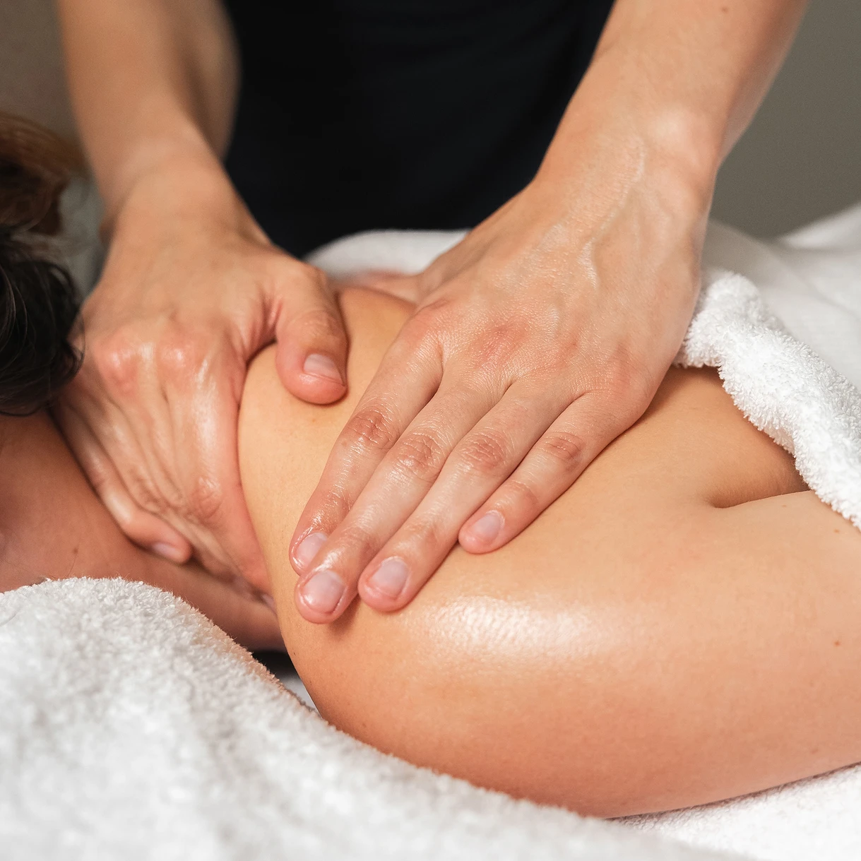 Gros plan sur des mains effectuant un massage profond des épaules au spa Les Hauts de Loire.