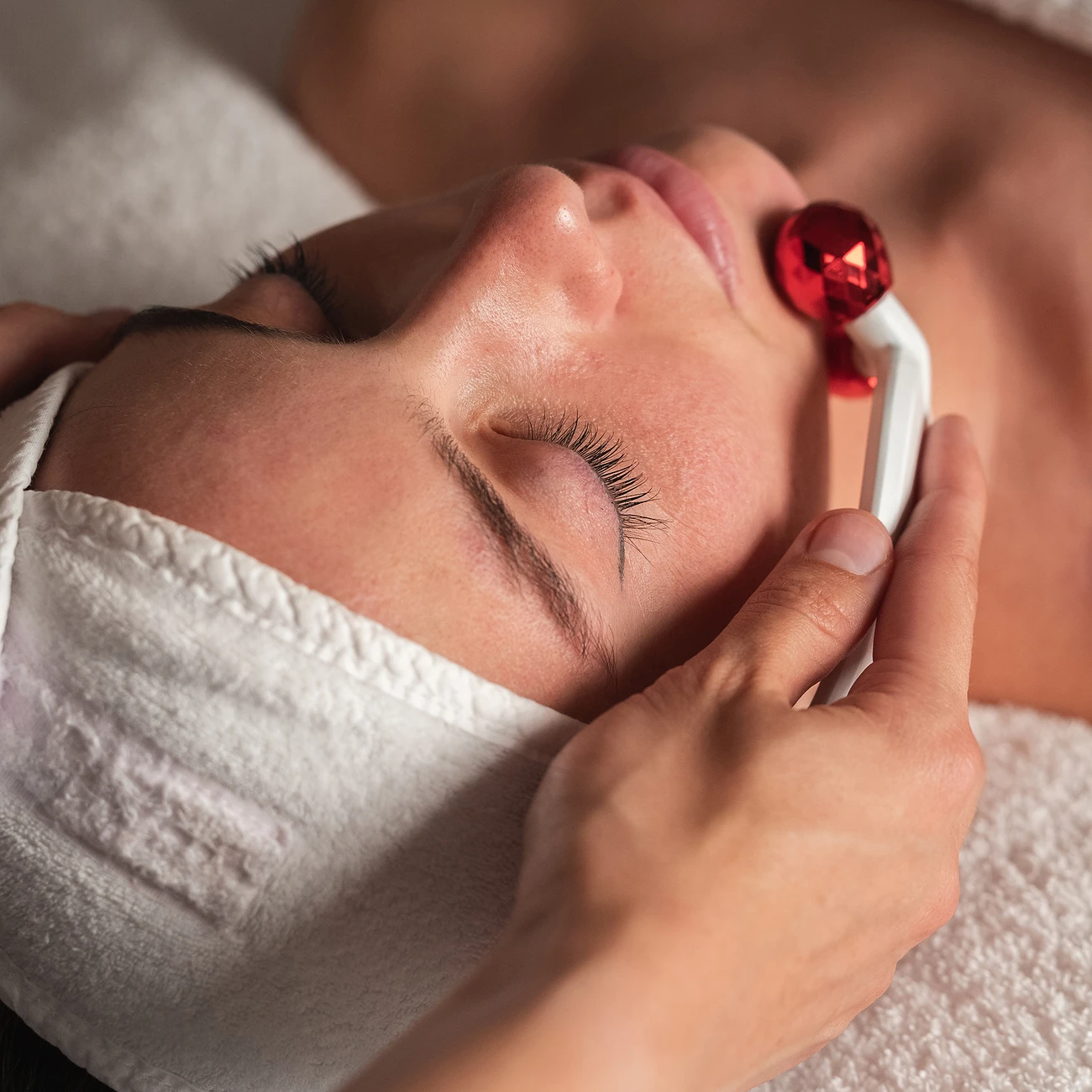 Soin du visage au rouleau de jade rouge dans une cabine de spa Les Hauts de Loire.