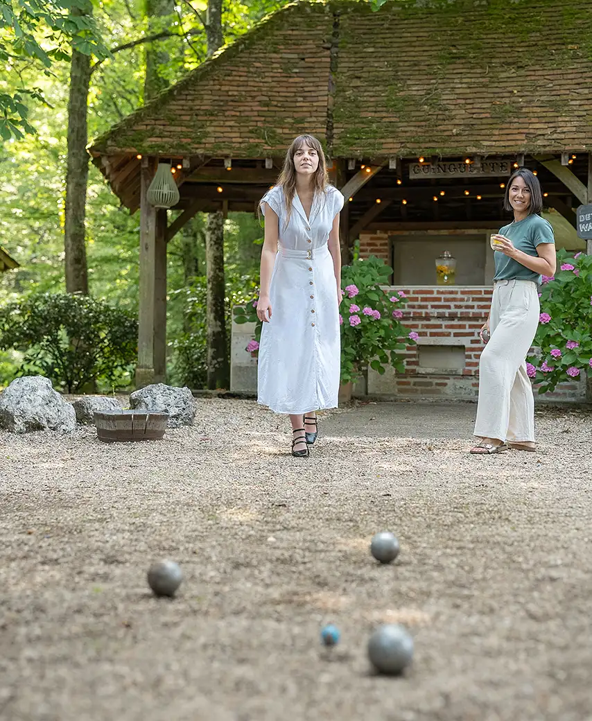 Deux femmes jouent à la pétanque sur un terrain en gravier dans le jardin de l'hôtel Les Hauts de Loire – Hôtel, Restaurant & Spa – 5 étoiles.