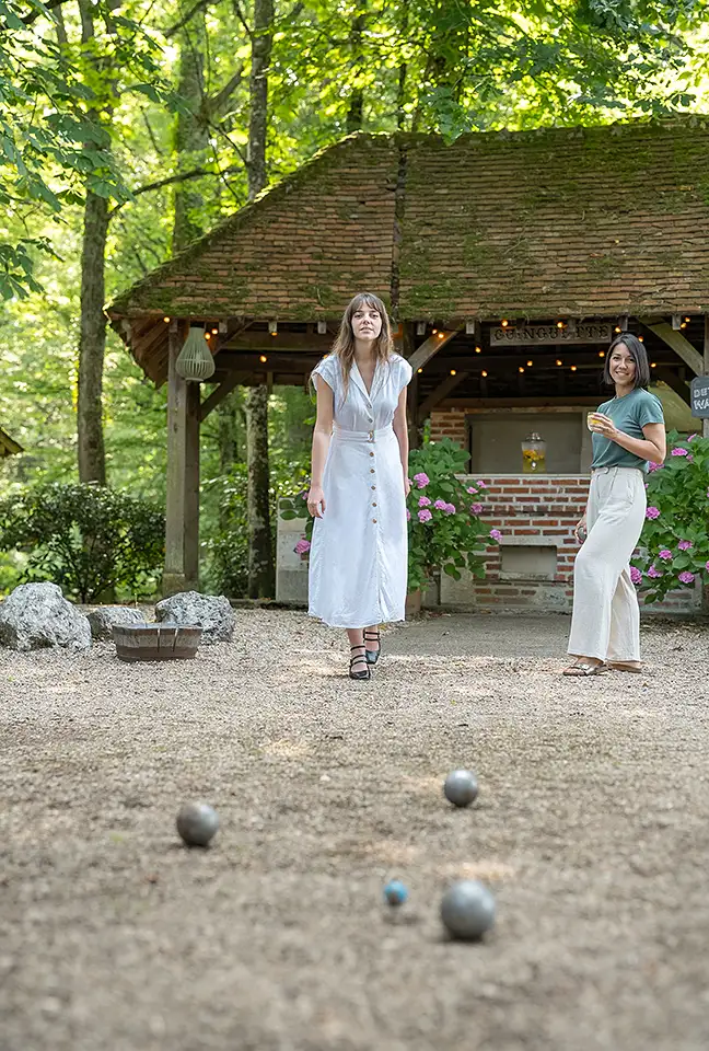 A slightly off-center view of the pétanque area, featuring the two women under the wooden pergola at Les Hauts de Loire – a 5-star hotel, restaurant, and spa.