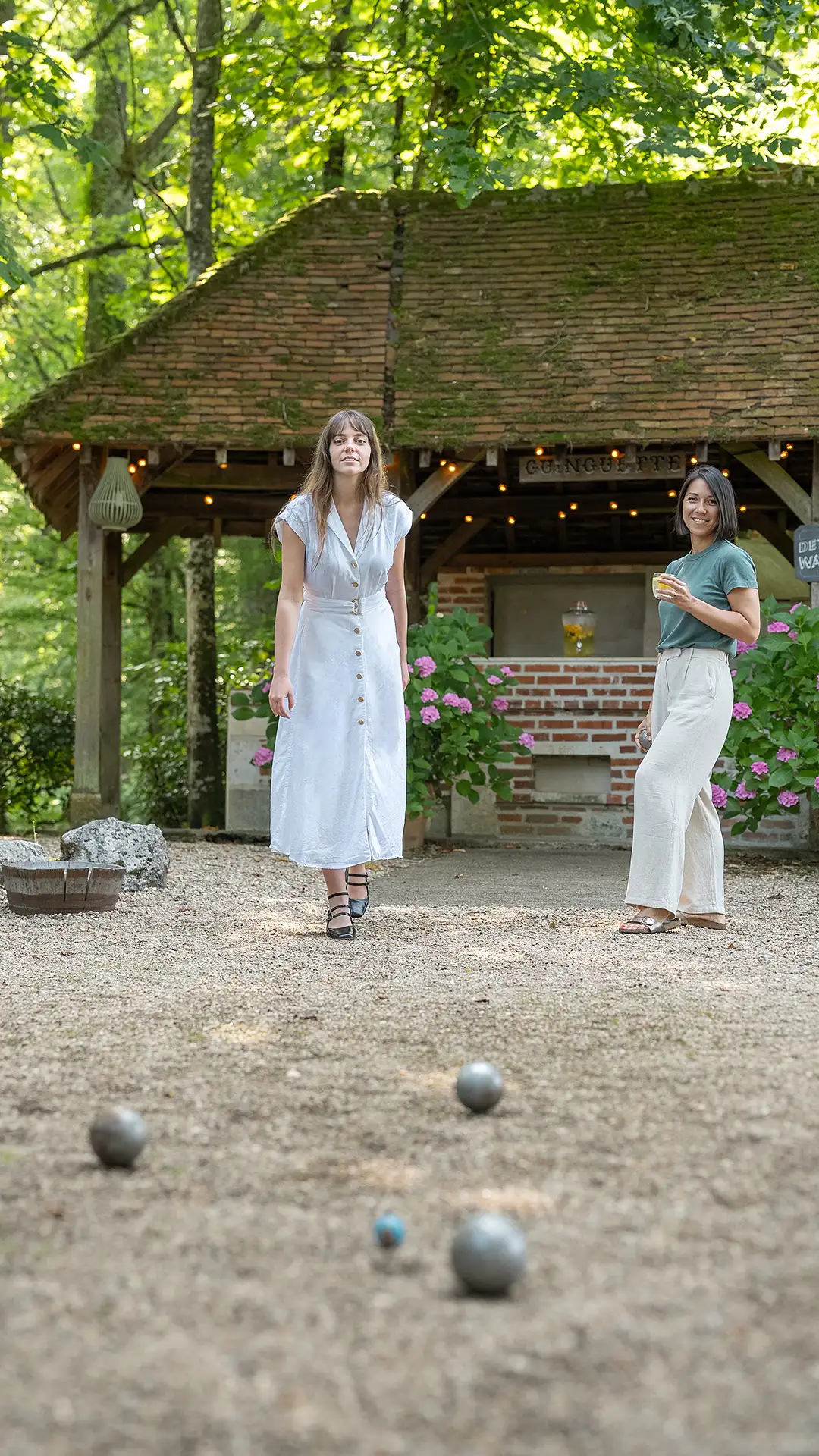 La joueuse en robe blanche est concentrée, prête à lancer sa boule sur le terrain de l'hôtel Les Hauts de Loire – Hôtel, Restaurant & Spa – 5 étoiles.