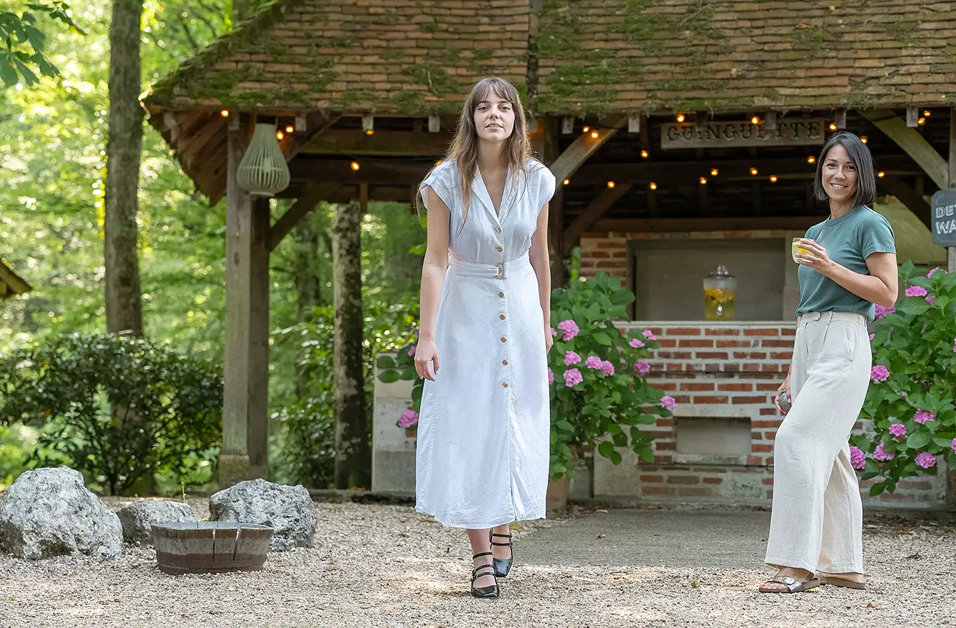 Les boules sont au premier plan alors que la femme en robe blanche s'apprête à jouer, devant la tonnelle de l'hôtel Les Hauts de Loire – Hôtel, Restaurant & Spa – 5 étoiles.