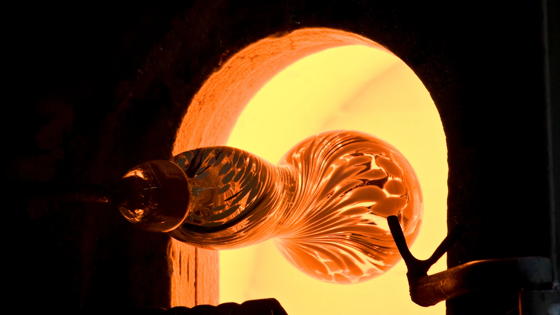 Le maître artisan façonne la pièce de verre incandescente, tournante, à l'intérieur du four.