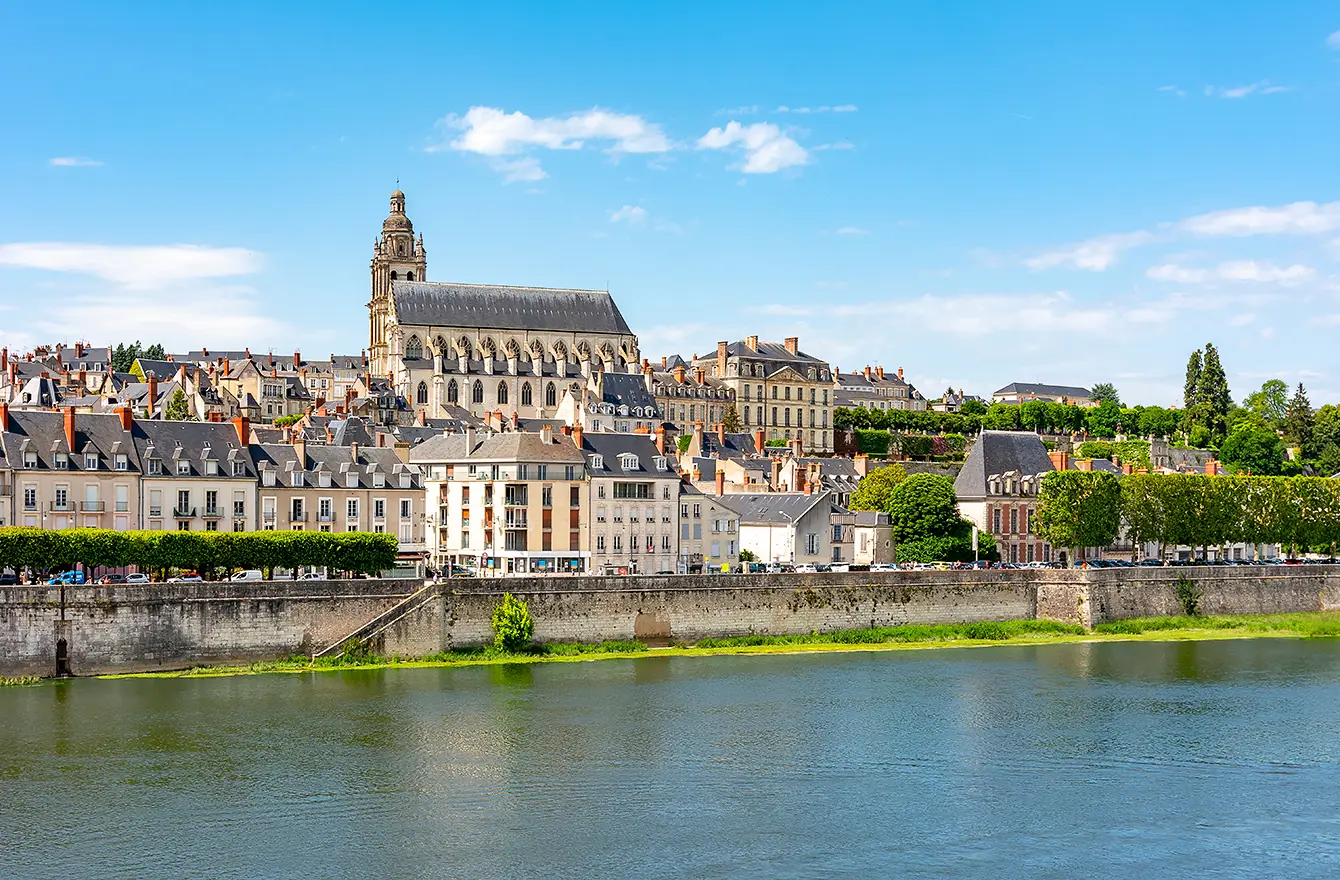 Rives verdoyantes et toits de pierre sous un ciel lumineux, un aperçu de Les Hauts de Loire – Hôtel, Restaurant & Spa – 5 étoiles.