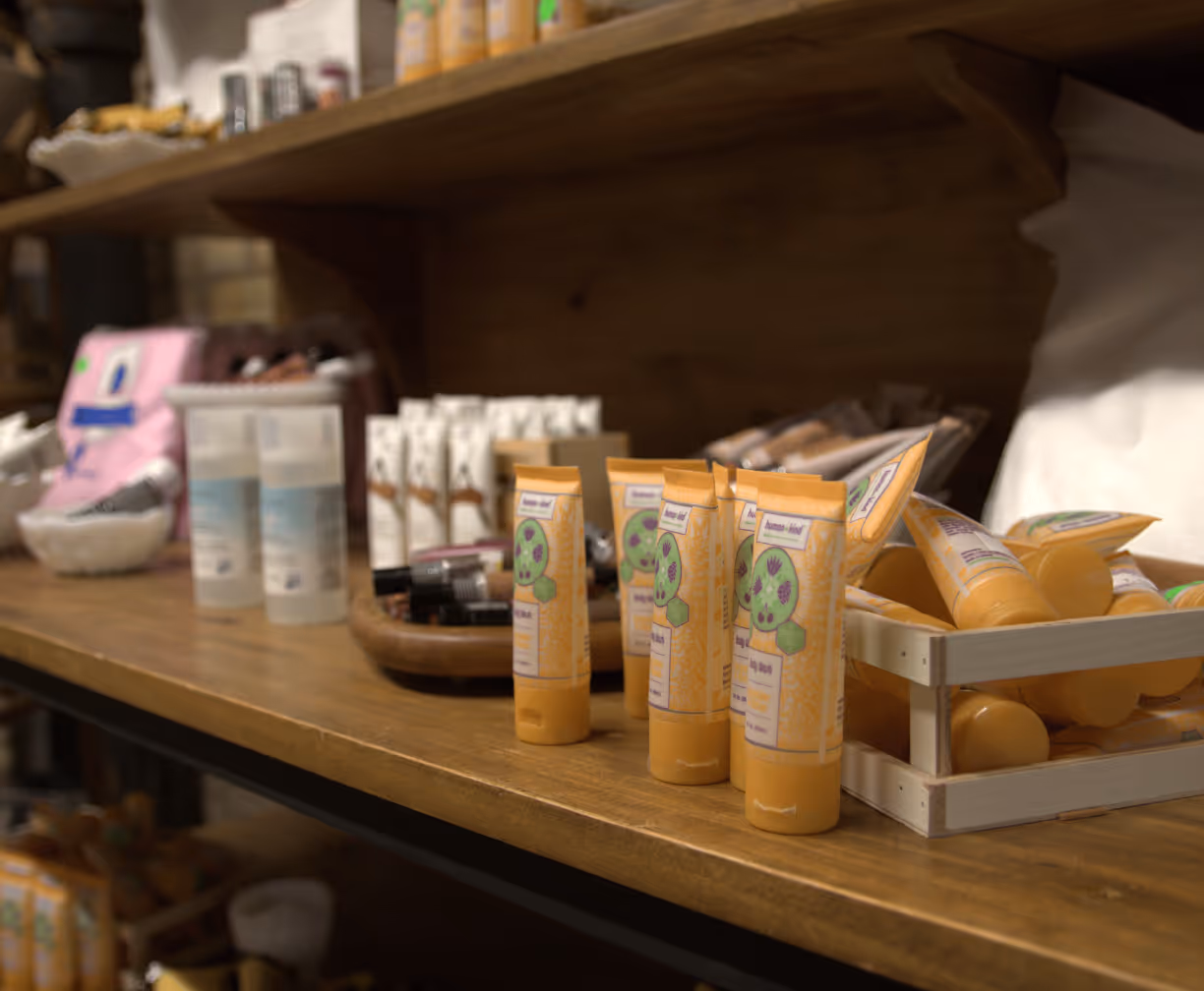 Wooden shelf displaying yellow skincare tubes and other cosmetic products in a store setting.
