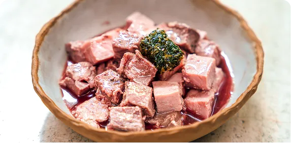 Bowl of diced fresh raw meat topped with greens