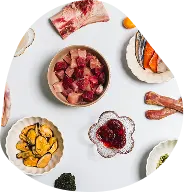 Whole-food ingredients laid out in bowls: diced meat, salmon, mussels, berries, bone and seaweed