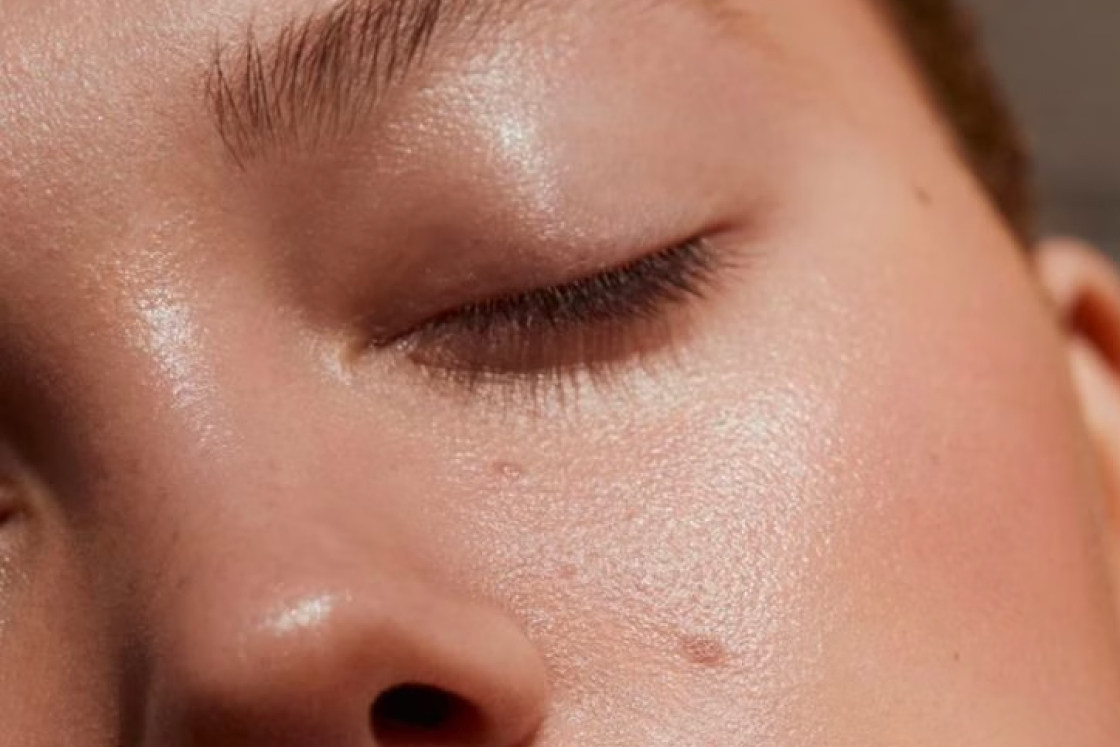Close-up of a person's closed eye and smooth skin with natural texture and slight shine.