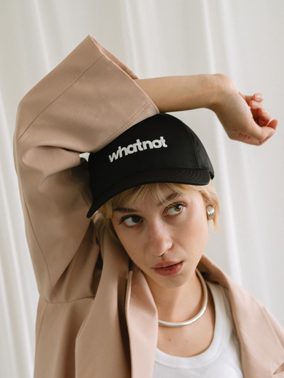 Whatnot custom black baseball cap with embroidered white logo on model