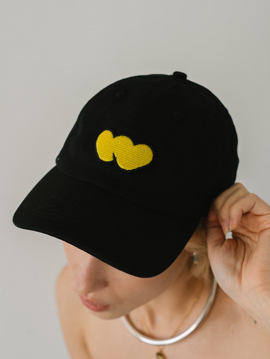 Whatnot custom black cap with embroidered yellow logo on model