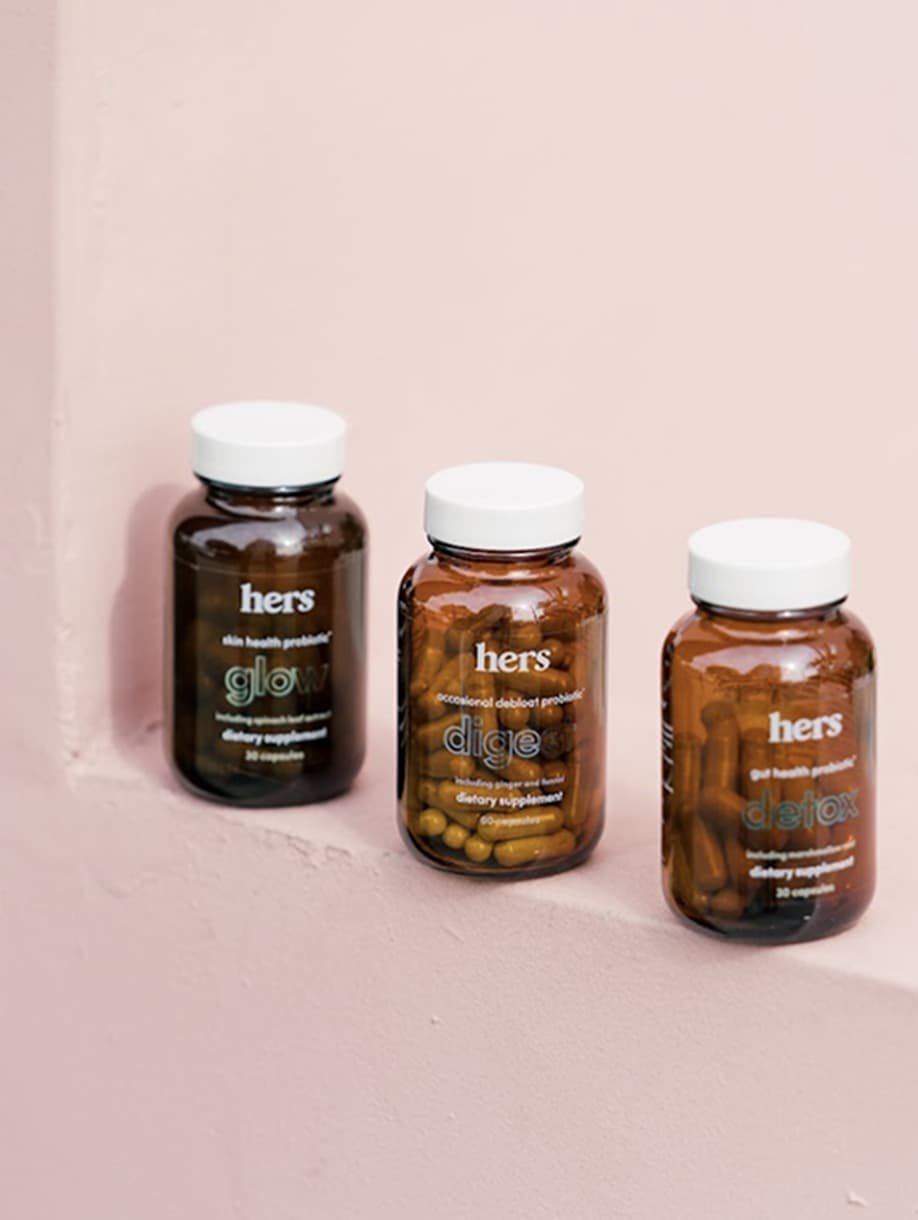 Hers wellness supplement bottles on pink background